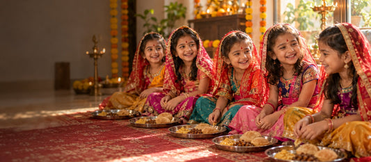 Little Indian girls in festive lehengas sitting in a row with halwa-puri thalis on Kanjak morning during Navratri
